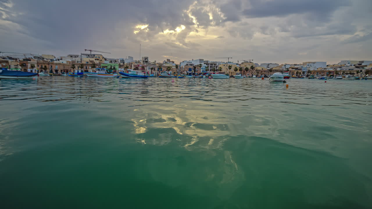 timelapse del puerto de marsaxlokk con barcos de pesca bajo un cielo nublado durante la puesta de sol, malta
