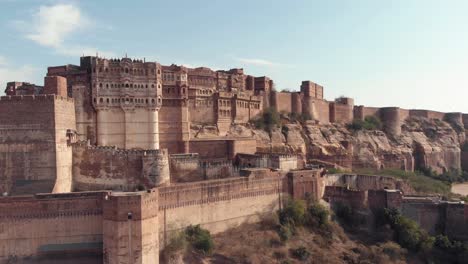 mehrangarh fort on a sunny day with birds flying around in jodhpur, rajasthan, india - aerial ascending establishing shot