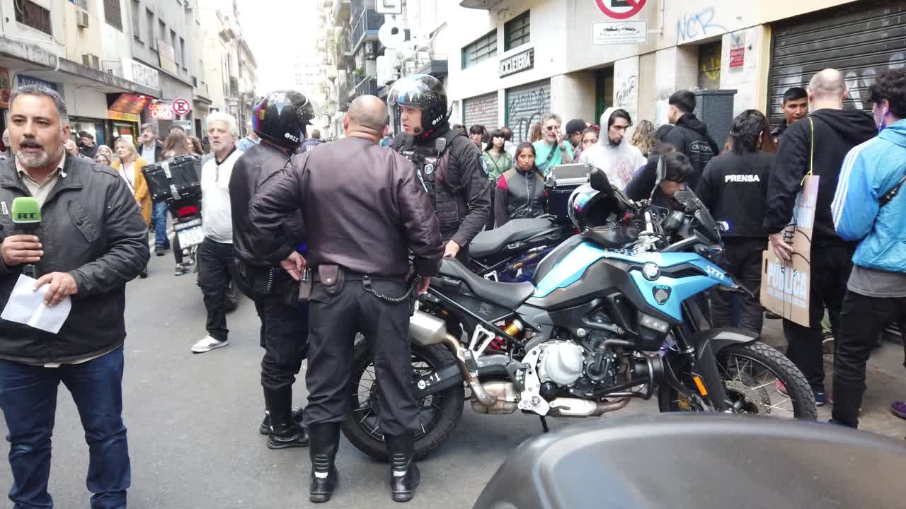 Police officers with blue lights and motorcycles arrest a girl in bustling protest, gather of people in congressional neighborhood center of buenos aires argentina