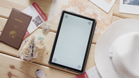 Flat-lay-of-tablet-with-copy-space,-passport-and-sunhat-on-wooden-background