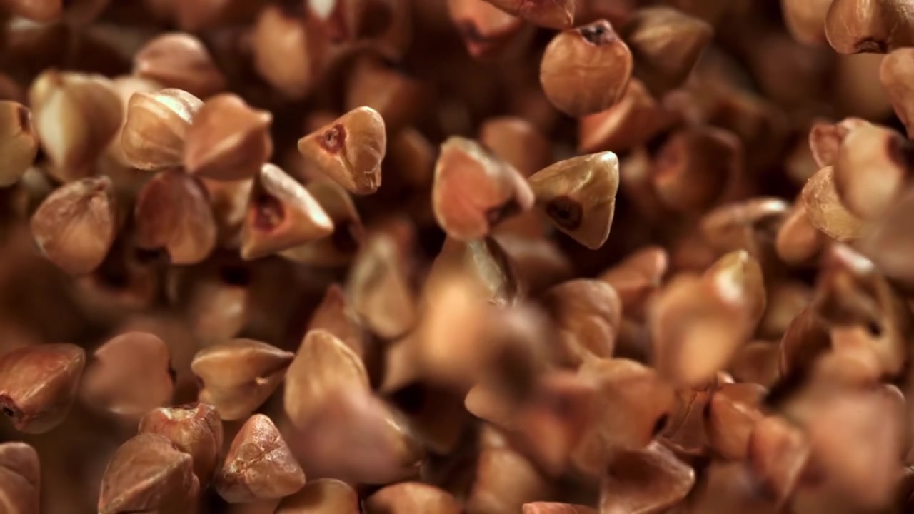 Grano saraceno crudo in caduta al rallentatore su sfondo nero
