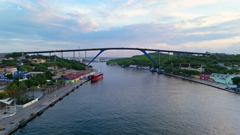 Aerial-dolly-to-Queen-Juliana-bridge-in-Willemstad-Curacao,-stunning-light-on-clouds-above-in-sky