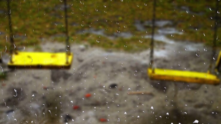 Swing during the rain. View from the window. Raindrops on the glass.