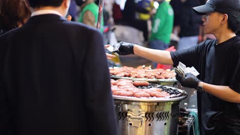 street food vendor selling grilled sausages at night market