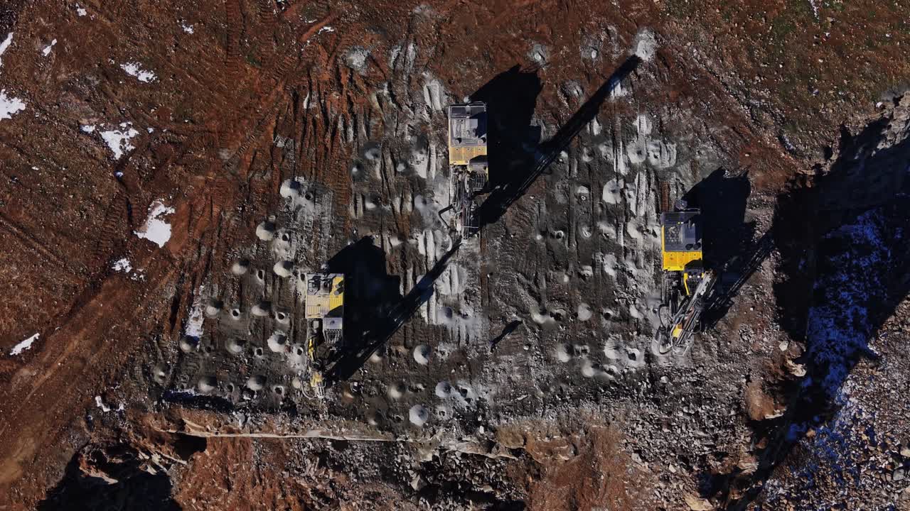 Lavori di costruzione in corso in un cantiere con macchinari su terreno roccioso.