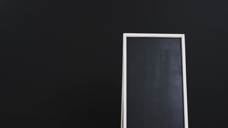 video of blackboard sign on white stand with copy space on black background