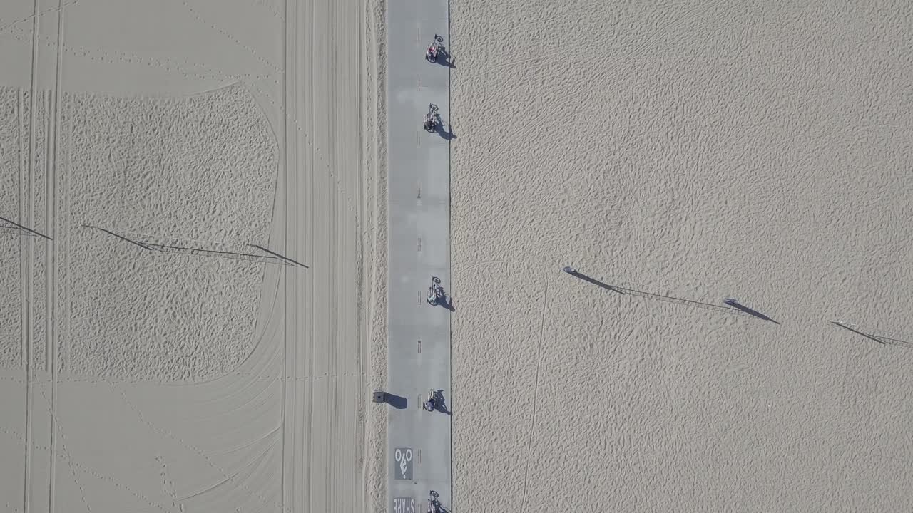 해변 산책로를 달리는 자전거를 탄 5명의 공중 드론 샷