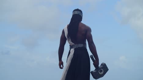 a muscular, dark-skinned man, true to nekharis in cosplay, is captured on a tropical beach