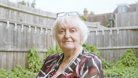 Elderly-Woman-smiling-at-camera-in-her-garden-day