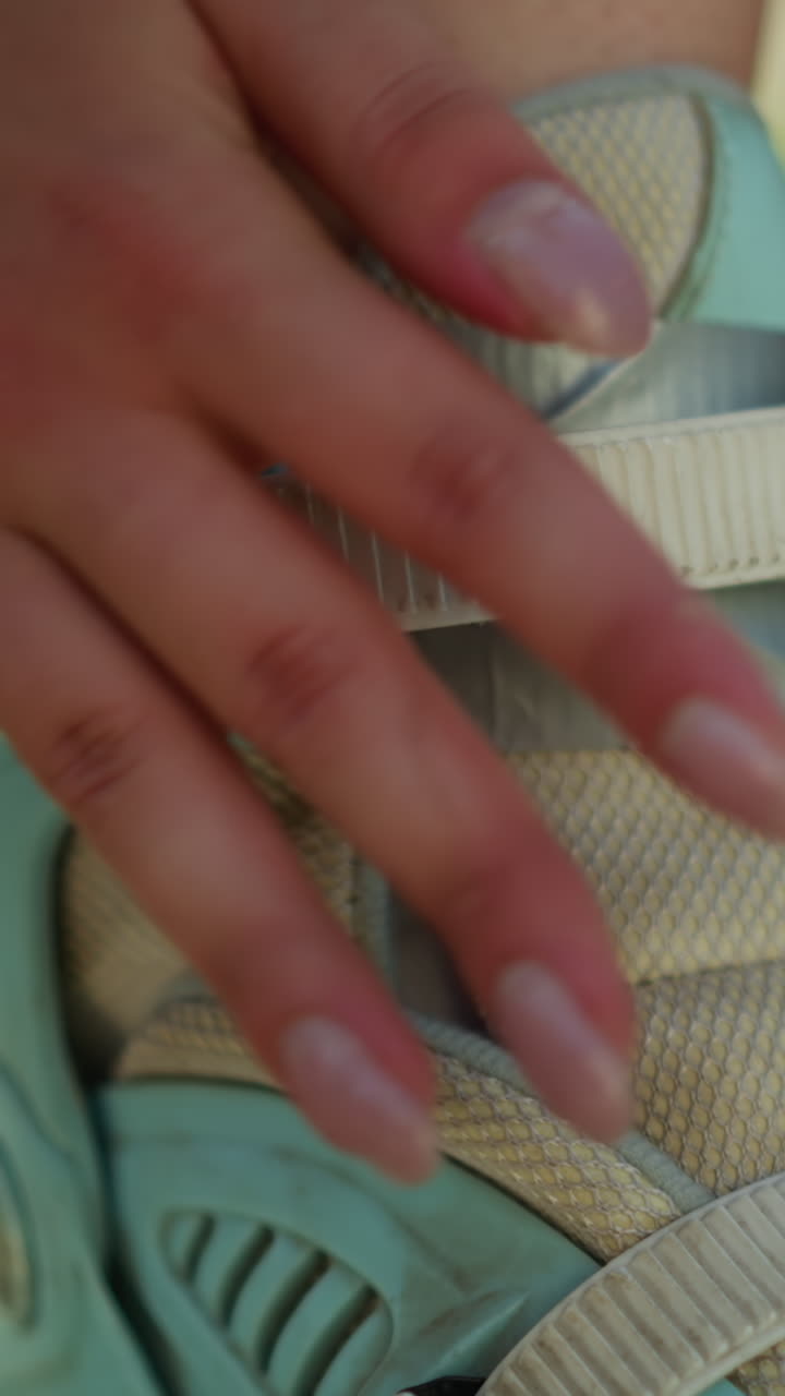 primer plano de las manos ajustando la correa en el zapato de patinaje sobre ruedas bajo la cálida luz del sol con fondo borroso, capturando detalles de los dedos apretando la corra para un ajuste seguro