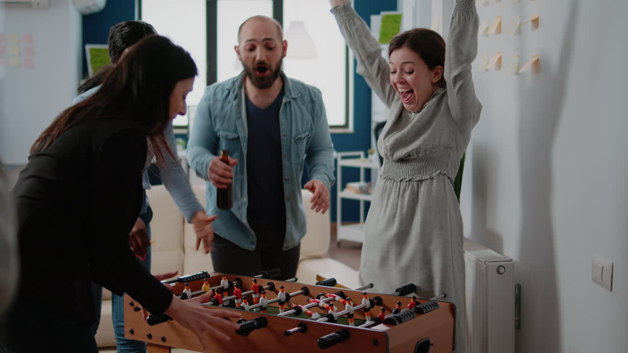 Colleagues playing foosball game and woman winning