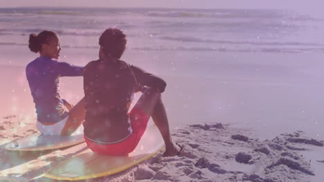 woman and man sitting on surfboards by ocean waves, health app showing floating data bubbles