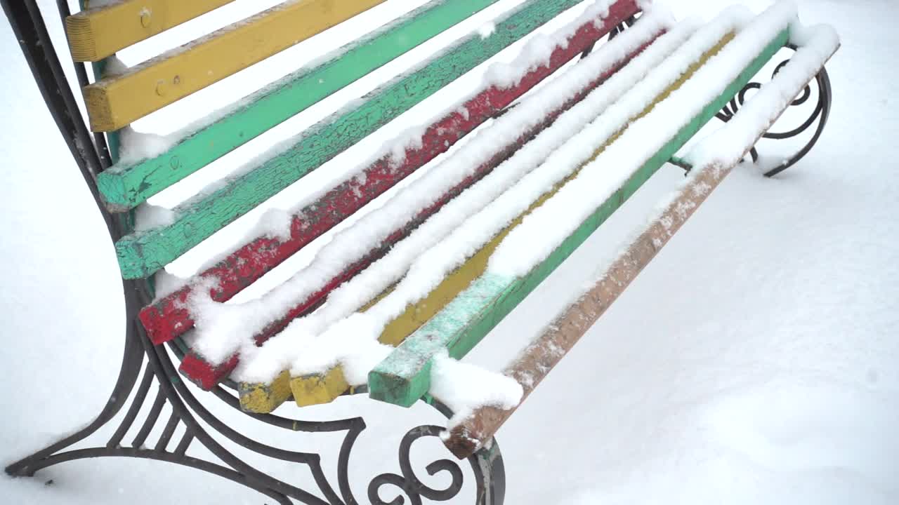 Bench in the square and the falling snow. Slow motion