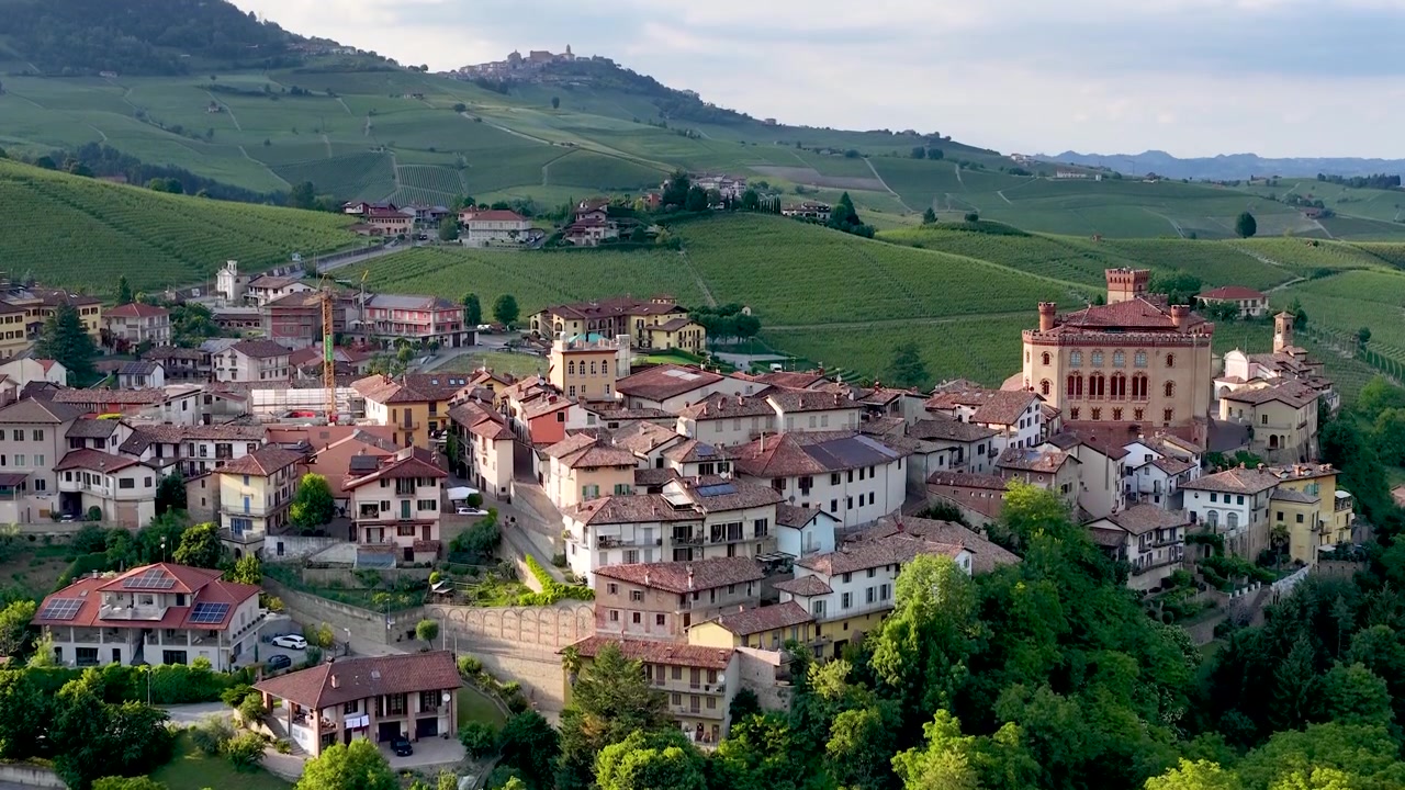 Un'ampia inquadratura statica riprende il borgo storico e il castello tra dolci colline vitate.