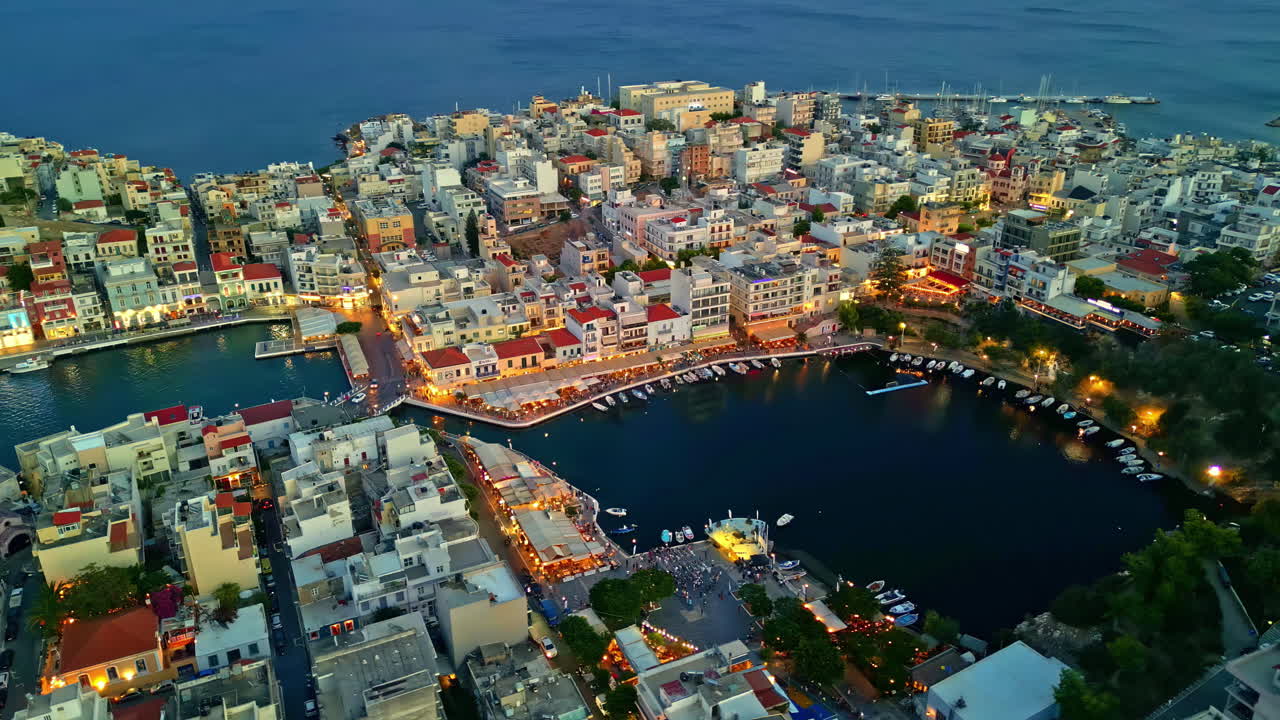 Rotating aerial view of Agios Nikolaos city during evening in Crete Island, Greece.