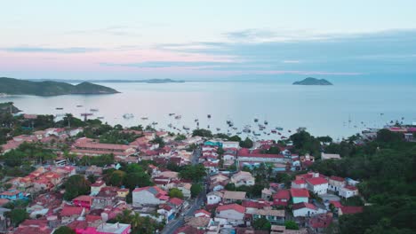 foto aérea de la playa da armação en búzios, brasil, al amanecer: contraste entre las casas y el bosque