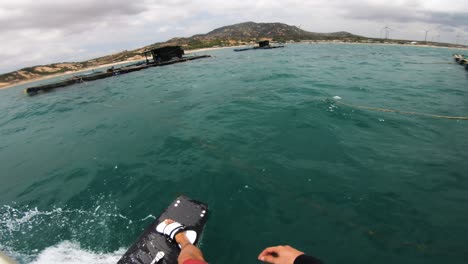 kitesurfista en un twin tip surfeando hacia granjas pesqueras en un mar contaminado en son hai, vietnam
