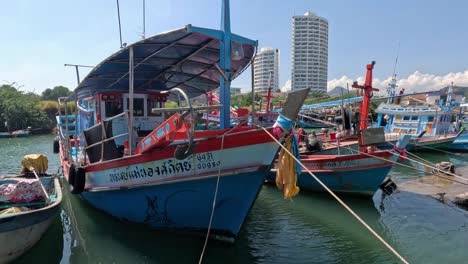 fishing boats maneuvering in a busy thai harbor.