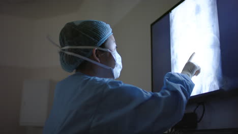 asian female surgeon looking at x-ray scans in operating theatre, slow motion