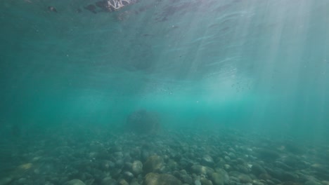 underwater shot of some waves crashing on the rocks on shore