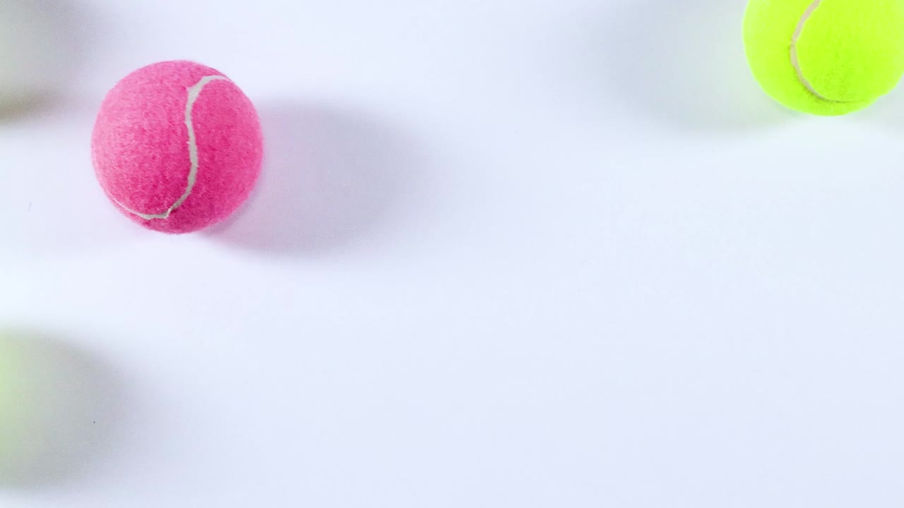 Brightly colored tennis balls scattered across a smooth white background, showcasing dynamic arrangement and vivid hues.