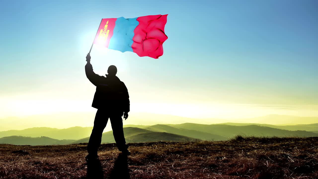 exitoso silueta hombre ganador agitando bandera de mongolia en la parte superior del pico de la montaña, fondo de bucle cinemagraph