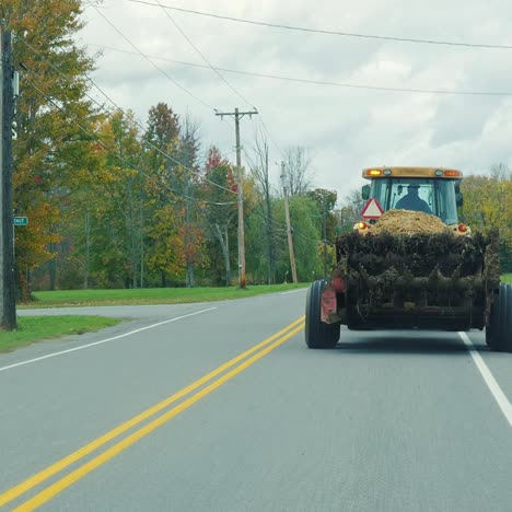 a slow tractor rides on a typical american road in the suburbs