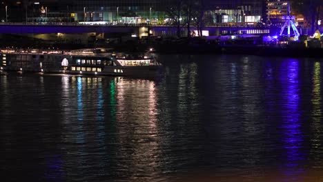 Capture-the-magic-of-Cologne-by-night-from-the-deck-of-a-cruise-ship,-as-it-drifts-serenely-along-the-Rhine-River,-offering-panoramic-views-of-the-city's-illuminated-landmarks-and-majestic-bridges