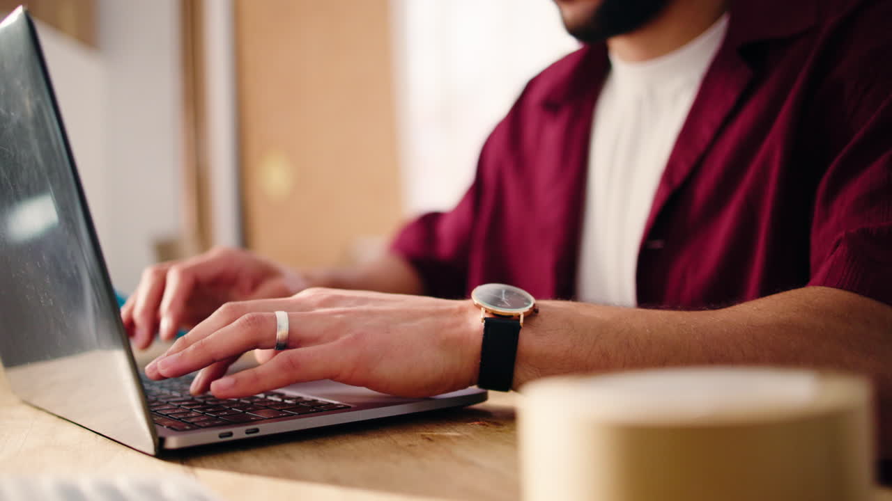 Close-up of Man's Hands Typing on Laptop Keyboard