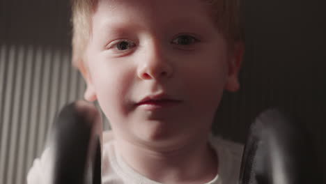 serious boy holds heavy barbell in hands looking in camera