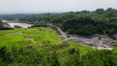 Dam-on-river-by-volcanic-sand-mine-near-Mount-Merapi,-Central-Java,-aerial-view