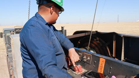 man in glasses and helmet watching the work of a rotating roller winding the wire. portrait of the engineer operating the drilling equipment at the oil production site.
