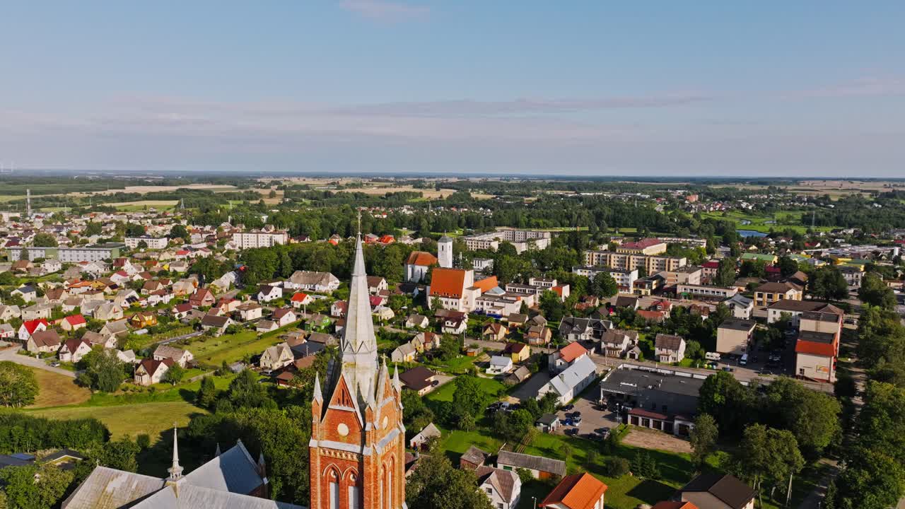 Forward drone over Kelme Lithuania iconic red church landmark with town below