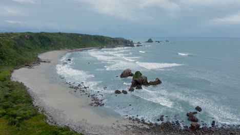 Aerial-view-of-remote-secluded-rugged-and-wild-bay-at-Cape-Foulwind-headland-and-the-Tasman-Sea-on-West-Coast,-South-Island-of-New-Zealand-Aotearoa