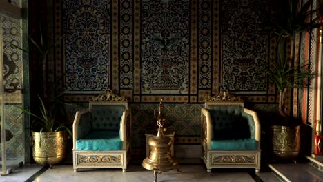 Ornate-room-with-traditional-Tunisian-tiles-and-royal-blue-chairs,-warm-lighting,-serene-ambiance