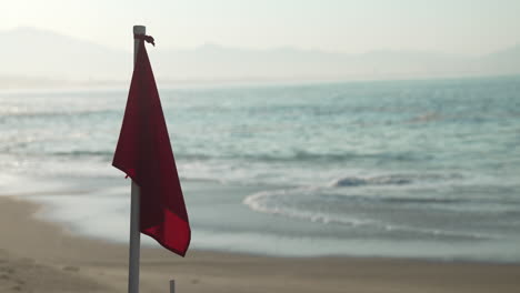 red flag at the beach warning of high hazard, dangerous surf, strong currents, use extreme caution