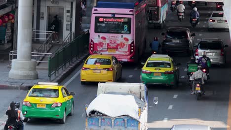 vehicles and motorbikes navigating crowded bangkok street