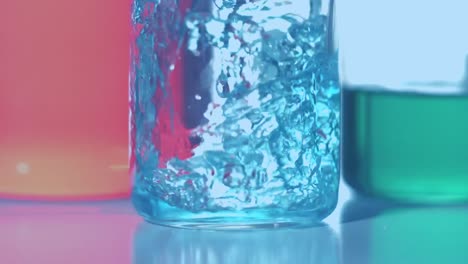 Animation-of-red-dots-floating-over-blue-reagent-pouring-into-glass