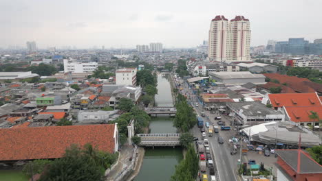 el tráfico ligero viaja a lo largo del canal kali krukut en el norte de yakarta, indonesia.