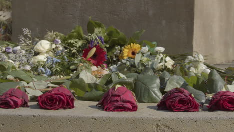 Dolly-of-withered-roses-at-base-of-statue