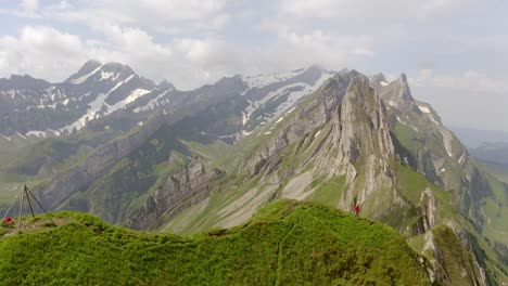 a man in a red jacket is walking on the edge of a mountain cliff