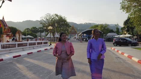 two women in traditional thai attire at a temple