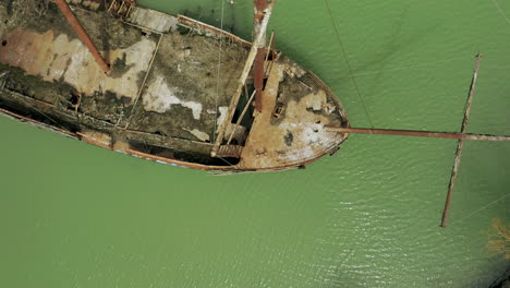 Rusty-red-shipwreck-stuck-in-shallow-green-water