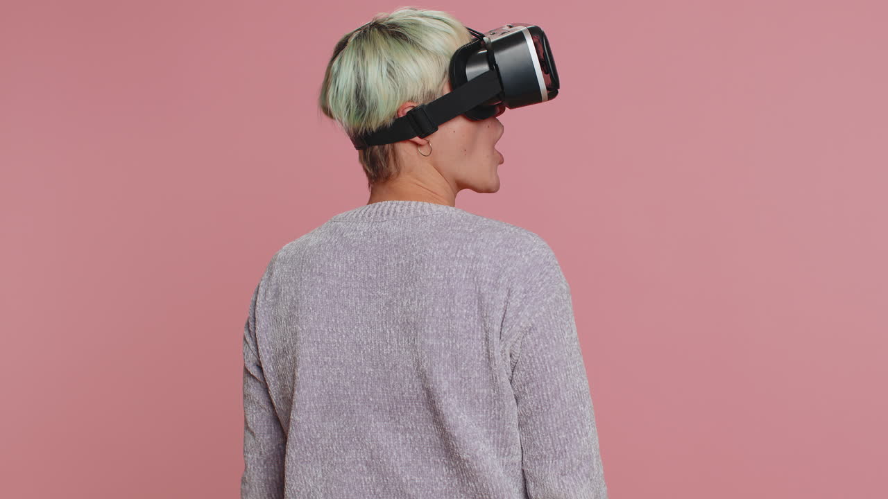 mujer joven usando casco de auriculares de realidad virtual para jugar aplicación de juego de simulación, viendo contenido de video