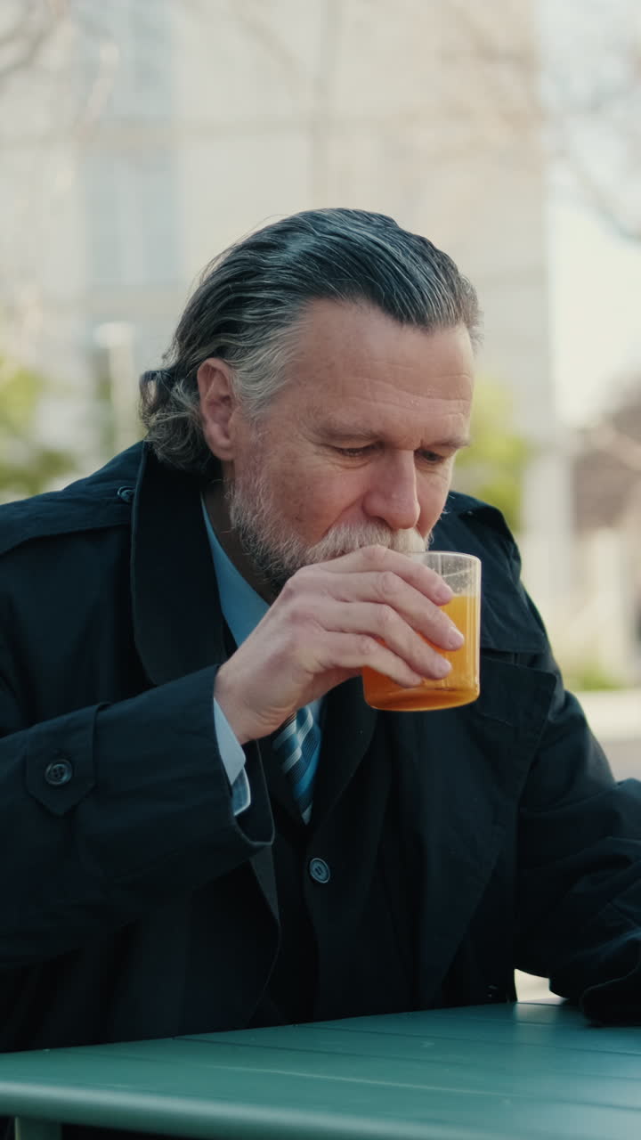 Businessman Enjoys Orange Juice and Checks Phone