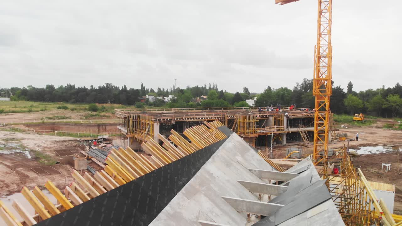 vista aérea elevada que muestra a los trabajadores de la construcción en equipo de seguridad contribuyendo enérgicamente a la construcción de una estructura altísima