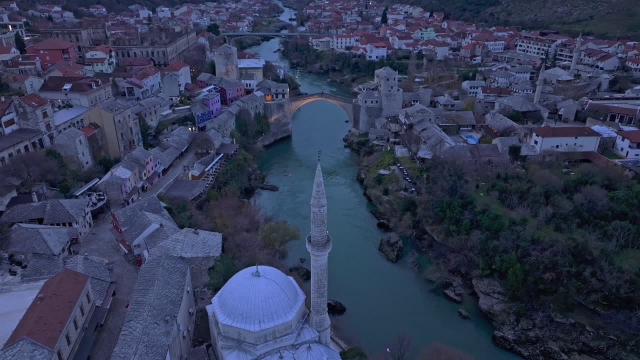 Aerial glimpse of Stari Most as the sun sets behind Mostar's skyline