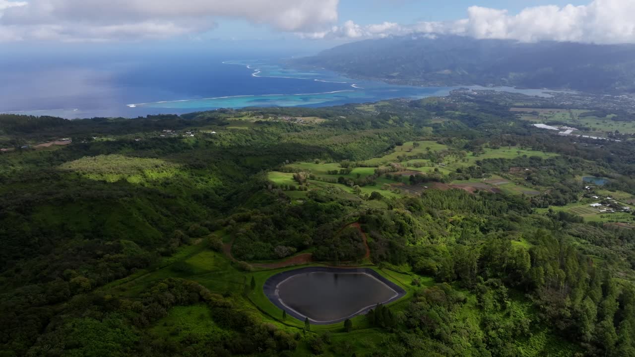 Aerial footage showing off the coast of Tahiti, French Polynesia. The coral reefs and the mountains on the coast are also visible on a partly cloudy day
