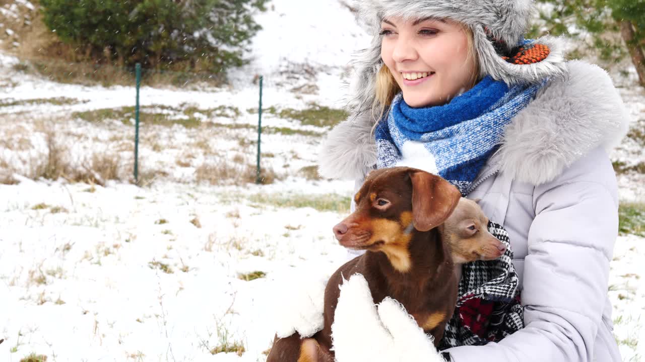 여자 는 겨울 밖 에서 작은 개 들 과 함께 놀고 있다