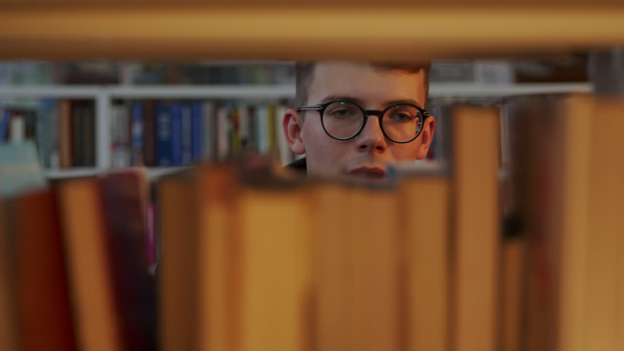 un joven buscando libros en una biblioteca